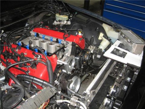 1996 Ford Thunderbird - The engine bay of a vehicle is shown with various components and wiring, along with an open manual.