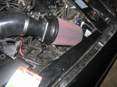 1996 Ford Thunderbird - Close-up of an engine bay, showing an aftermarket air intake system with a red cone filter.