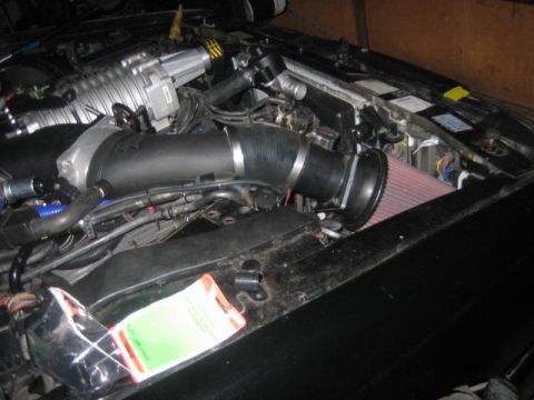 1996 Ford Thunderbird - Close-up view of a modified engine bay, a prominent supercharger and aftermarket air intake system.