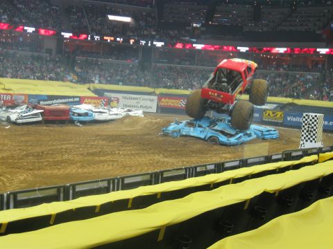 1994 Ford Bronco - Monster truck event with multiple crushed cars on the dirt track.