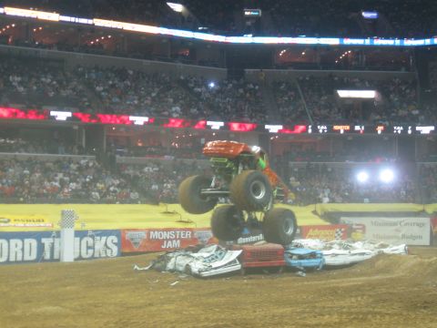 1994 Ford Bronco - A monster truck performs a jump over several wrecked cars during a Monster Jam event.