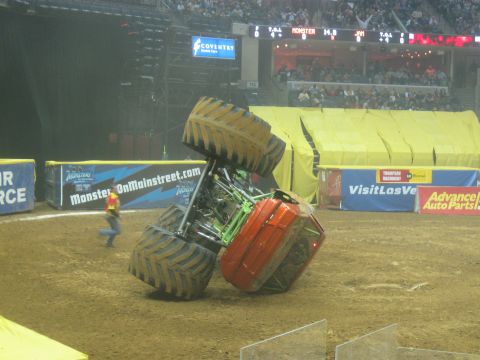 1994 Ford Bronco - An overturned monster truck lies on a dirt arena floor during a competition.