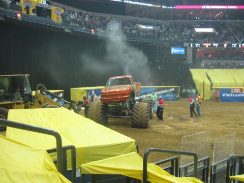 1994 Ford Bronco - A monster truck sits in an arena, emitting smoke as people gather around.