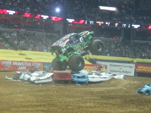 1994 Ford Bronco - Monster truck performs a jump over a pile of wrecked cars during a Monster Jam event.