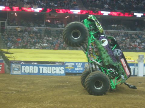 1994 Ford Bronco - A monster truck, identified as Grave Digger, is captured mid-air performing a wheelie during an event.