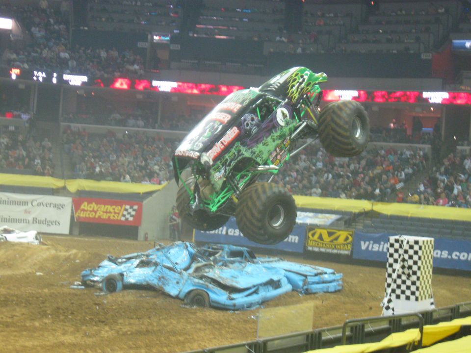 Monster truck jumping over two crushed cars in an arena