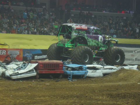 1994 Ford Bronco - The Grave Digger monster truck is shown in action, crushing cars during a Monster Jam event.