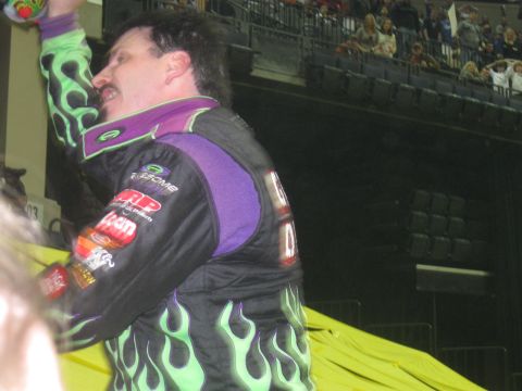 1994 Ford Bronco - A driver celebrates a victory in an arena, holding up a trophy.