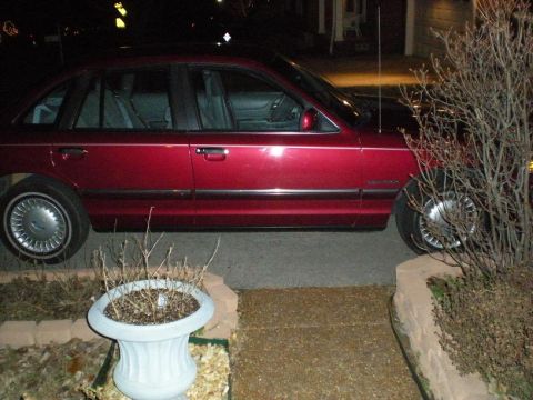 1994 Ford Crown Victoria - Side view of a red 1994 Ford Crown Victoria parked outside at night.