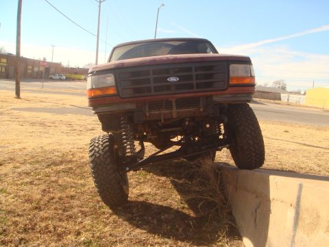 1992 Ford Bronco - A lifted 1992 Ford Bronco is positioned with its front wheels on a concrete barrier.