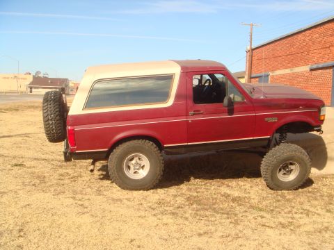 1992 Ford Bronco - This red 1992 Ford Bronco is shown from the side, a spare tire mounted on the rear.