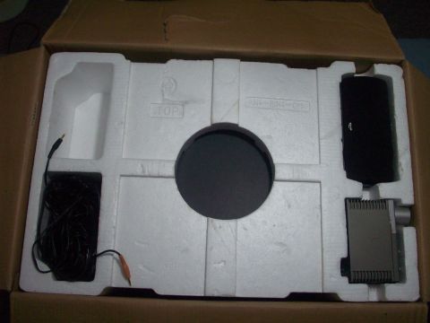 2006 Ford F-150 - Unpacked electronic device components with cables and a circular part within a cardboard box.