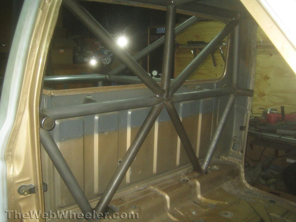 Bare-metal X-brace roll cage tubing inside a stripped vehicle cab