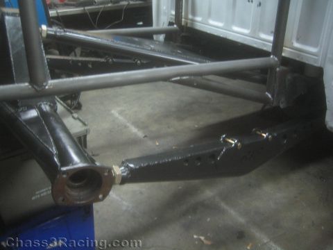 1990 Ford Bronco - bare-metal fabricated tubular suspension arm with a round flange end is mounted to a chassis just above the shop concrete floor.