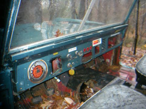 1978 Ford Bronco - The interior of a vehicle shows a teal dashboard with various controls and a floor littered with fallen leaves.