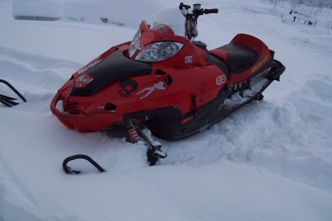 2004 Arctic Cat F-7 Firecat - A red snowmobile sits partially buried in snow, displaying several decals and the 'Arctic Cat' branding on its side.