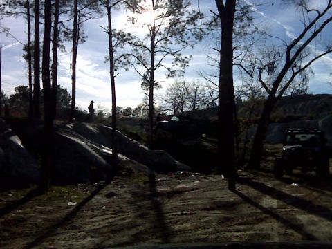 2008 Jeep Wrangler - A Jeep Wrangler is parked on a dirt path surrounded by trees and rocky terrain.