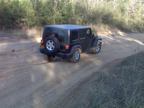 2008 Jeep Wrangler - Black 2008 Jeep Wrangler driving on a dirt road through trees.