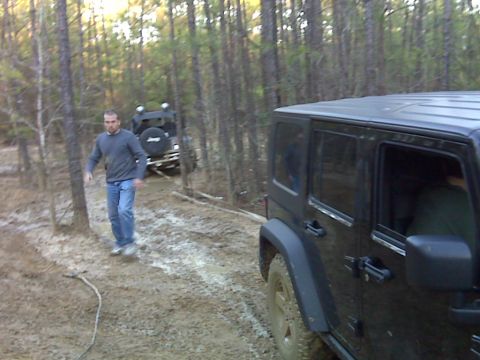 2008 Jeep Wrangler - Two Jeeps navigate a muddy trail through a wooded area.