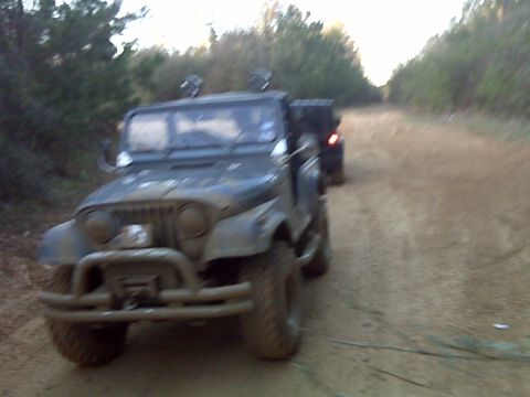 2008 Jeep Wrangler - Two off-road vehicles travel down a dirt path lined with trees.