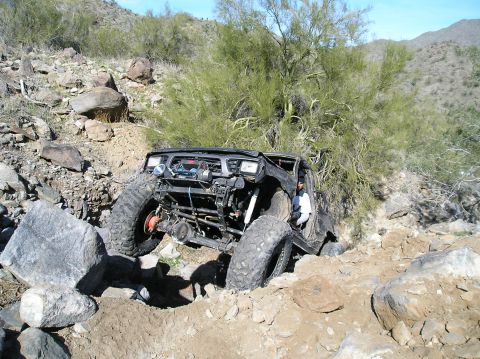1986 Toyota Hilux - This heavily modified off-road vehicle is shown navigating a challenging rocky trail.