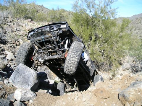 1986 Toyota Hilux - This heavily modified truck is attempting to climb over large rocks in a desert environment.