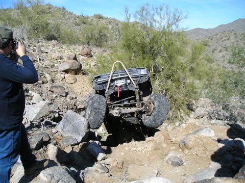 1986 Toyota Hilux - Off-road vehicle navigating a steep, rocky incline under a clear blue sky.