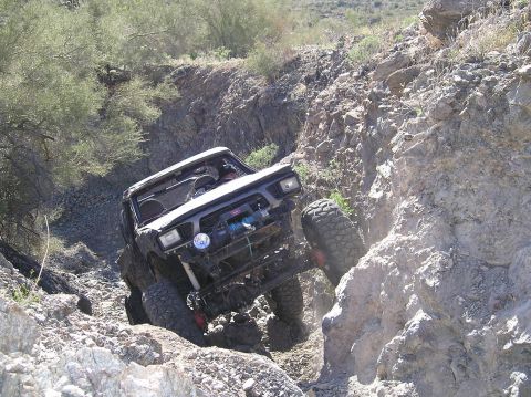 1986 Toyota Hilux - This modified Toyota Hilux navigates a steep, rocky incline in an off-road environment.