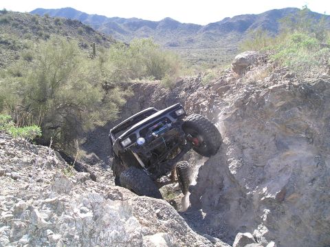 1986 Toyota Hilux - Modified 1986 Toyota Hilux navigates a challenging rocky trail in a desert environment.