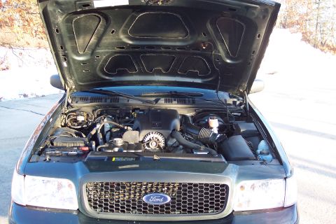 2001 Ford Crown Victoria - Engine bay of a dark green Ford Crown Victoria, showing the engine and front grille.
