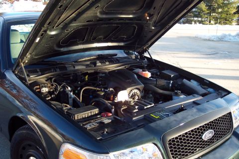 2001 Ford Crown Victoria - The engine bay of a 2001 Ford Crown Victoria is visible with the hood open, revealing the engine and surrounding components.