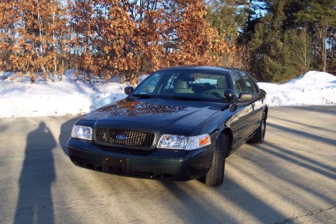 2001 Ford Crown Victoria - A dark green Ford Crown Victoria is parked outside on a sunny day with snow on the ground.
