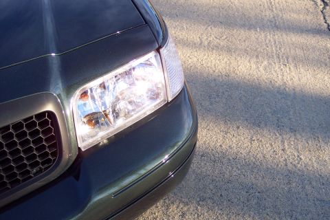 2001 Ford Crown Victoria - Front corner view of a dark green 2001 Ford Crown Victoria, its distinctive honeycomb grille and clear headlight assembly.