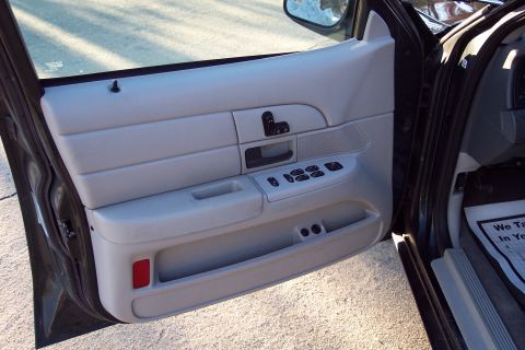 2001 Ford Crown Victoria - Close-up of the interior door panel, showing the window controls and a red reflector on the lower section.