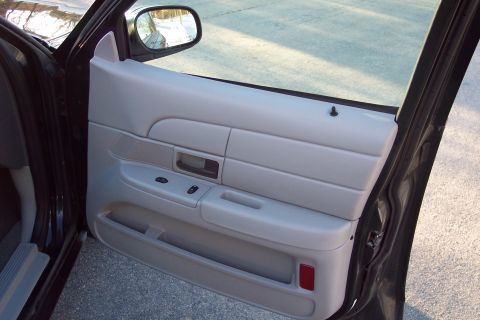 2001 Ford Crown Victoria - Interior view of a car's gray door panel, showing window controls and a red reflector.