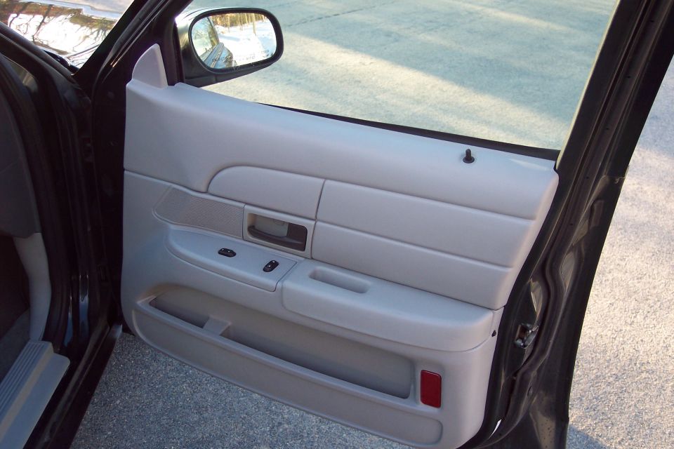 Gray interior door panel with window controls and a red reflector