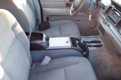 2001 Ford Crown Victoria - The interior of a car, cloth seats and a center console with cup holders.