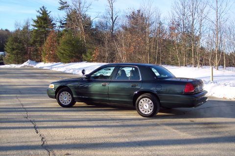 2001 Ford Crown Victoria - A dark green 2001 Ford Crown Victoria is parked on a road with snow on the sides.