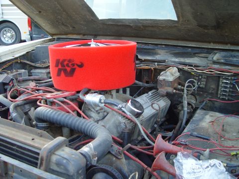1968 Ford Mustang - Close-up of an engine bay a prominent red K&N air filter and Holley valve covers, with visible wiring and other engine components.
