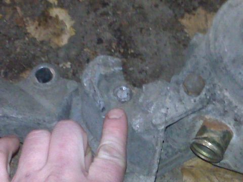 1995 Ford Bronco - A close-up view of a metal engine block component with a bolt and a brass fitting.