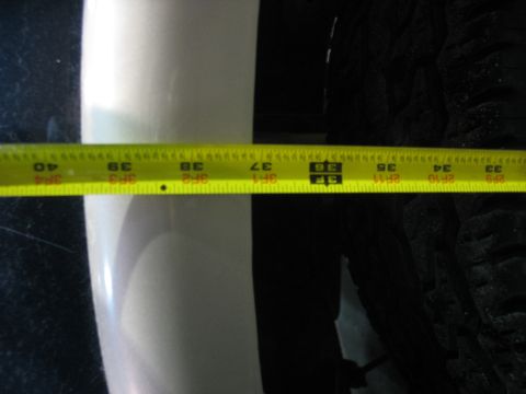 1995 Ford C-350 (Centurion Conversions) - A yellow measuring tape is positioned over a tire and a white vehicle body panel.