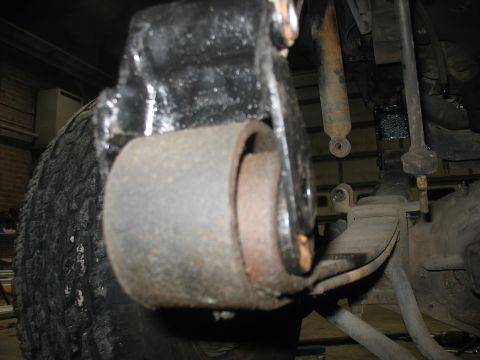 1995 Ford C-350 (Centurion Conversions) - Detail of a vehicle's suspension system, focusing on the leaf spring and shackle mount.