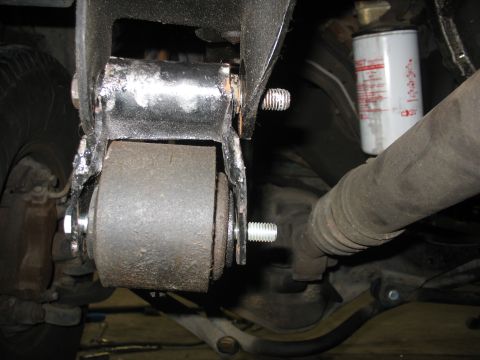 1995 Ford C-350 (Centurion Conversions) - Detail of a vehicle's suspension system, showing a bushing and mounting hardware, with an oil filter in the background.