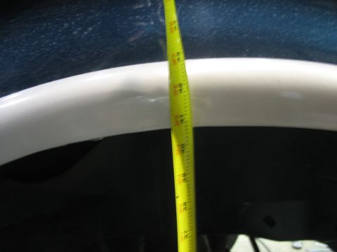 1995 Ford C-350 (Centurion Conversions) - A yellow measuring tape is used to measure the height of a vehicle's wheel well.