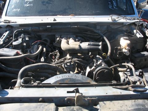 1987 Ford Bronco - The engine bay of a vehicle, with a "CAUTION FAN" shroud prominently displayed.