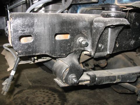 1995 Ford C-350 (Centurion Conversions) - Close-up view of a vehicle's front suspension system, showing a leaf spring and mounting bracket.