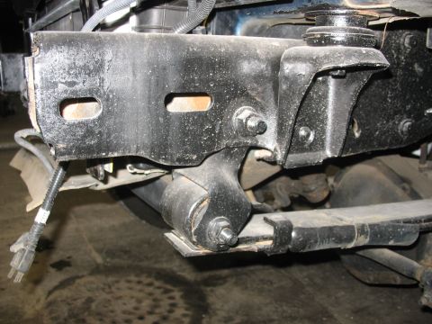 1995 Ford C-350 (Centurion Conversions) - Close-up view of a vehicle's front suspension components, including a heavy-duty bracket and leaf spring.