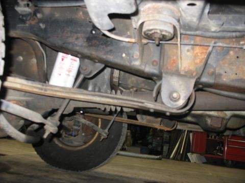 1995 Ford C-350 (Centurion Conversions) - A close-up view of the undercarriage reveals the vehicle's suspension components and a white oil filter.