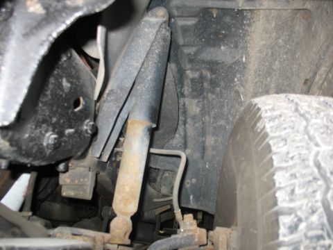 1995 Ford C-350 (Centurion Conversions) - This image shows a close-up view of the suspension system, including a shock absorber and various metal components.