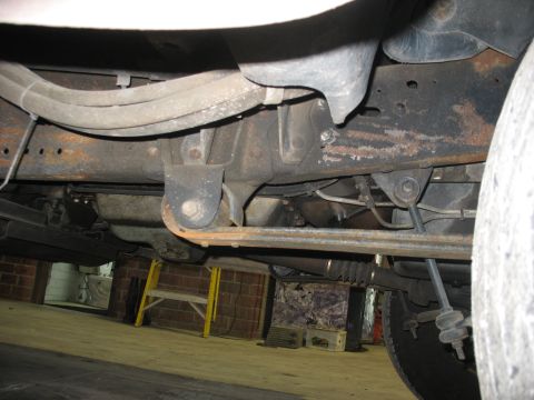 1995 Ford C-350 (Centurion Conversions) - The underside of a truck reveals its suspension system, including leaf springs and frame components.